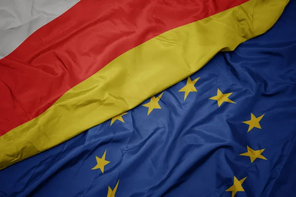 Waving colorful flag of european union and flag of south ossetia. — Stock Photo, Image