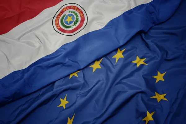 Ondeando colorida bandera de la unión europea y bandera de paraguay . —  Fotos de Stock