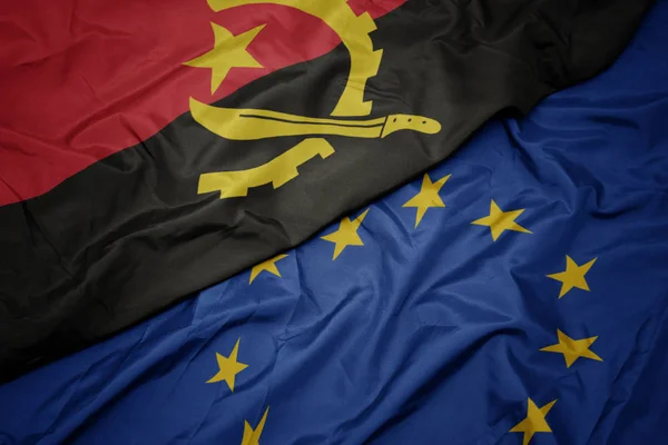 Waving colorful flag of european union and flag of angola. — Stock Photo, Image