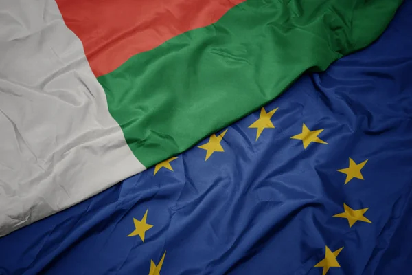 Waving colorful flag of european union and flag of madagascar. — Stock Photo, Image