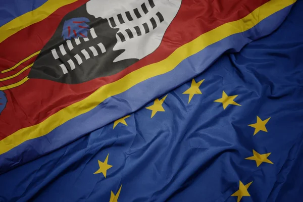 Agitant drapeau coloré de l'union européenne et drapeau du Swaziland . — Photo