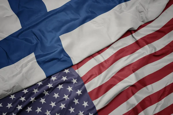 Falujące kolorowe flagi Stanów Zjednoczonych Ameryki i flagi narodowej Finlandii. — Zdjęcie stockowe