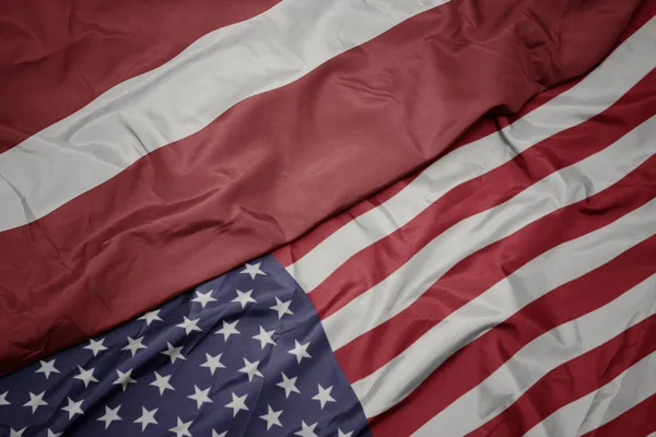 Waving colorful flag of united states of america and national flag of latvia. macro — Stock Photo, Image