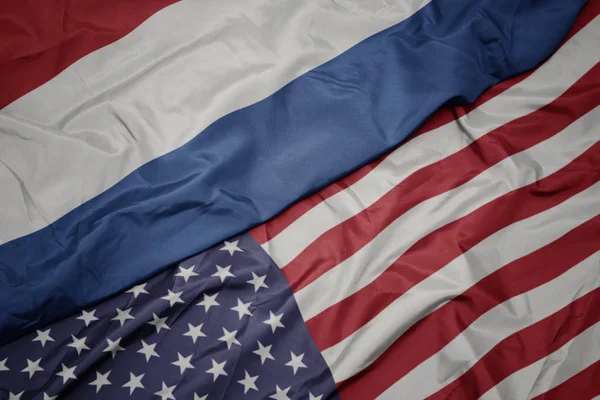 Mávající barevnou vlajku Spojených států amerických a národní vlajky Nizozemska. Makro — Stock fotografie
