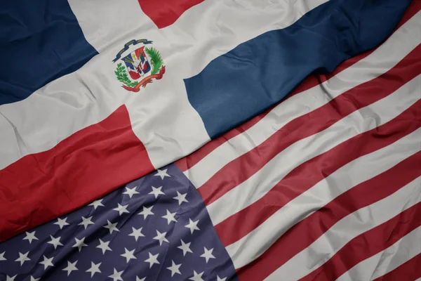 Ondeando colorida bandera de Estados Unidos de América y bandera nacional de República Dominicana . — Foto de Stock