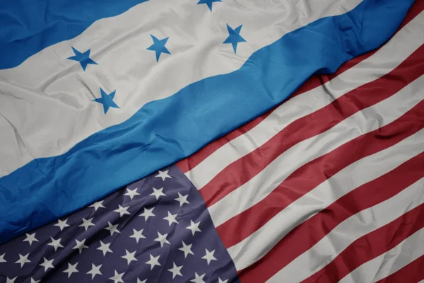 Ondeando colorida bandera de estados unidos de america y bandera nacional de honduras . — Foto de Stock