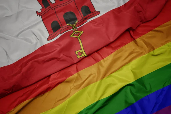 挥舞着五颜六色的同性恋彩虹旗和直布罗陀国旗. — 图库照片