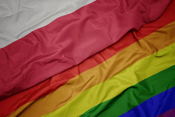 Waving colorful gay rainbow flag and national flag of poland. — Stock Photo, Image