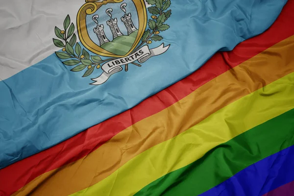 Zwaaiende kleurrijke Gay regenboog vlag en nationale vlag van San Marino. — Stockfoto
