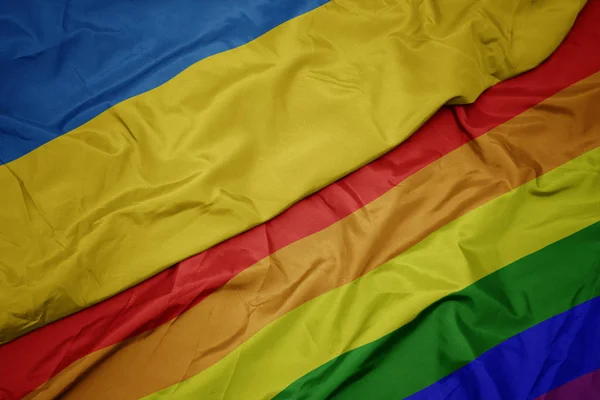 Κυματιστό πολύχρωμο gay ουράνιο τόξο σημαία και την εθνική σημαία της Ουκρανίας. — Φωτογραφία Αρχείου