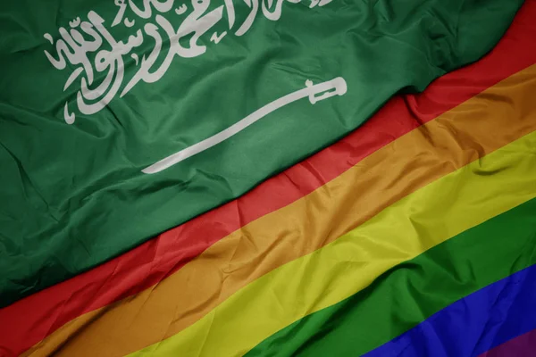 挥舞着五颜六色的同性恋彩虹旗和沙特阿拉伯国旗. — 图库照片
