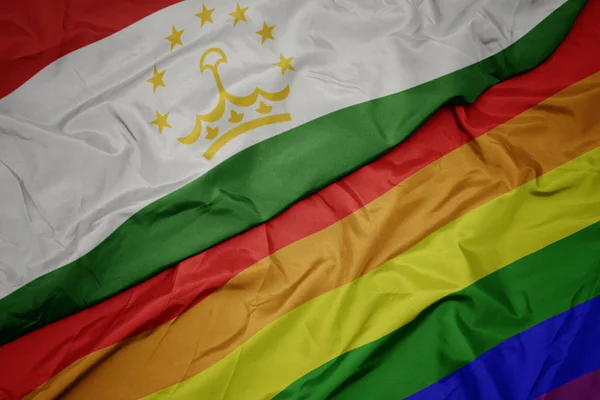 Waving colorful gay rainbow flag and national flag of tajikistan. — Stock Photo, Image