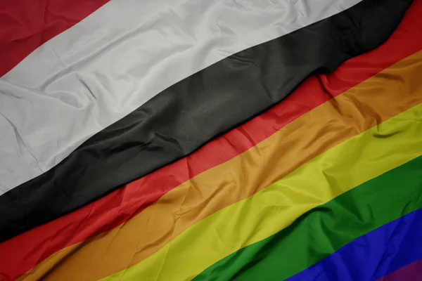 Machając kolorowe gej tęczowa flaga i flaga Jemen. — Zdjęcie stockowe