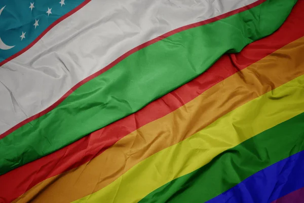 Waving colorful gay rainbow flag and national flag of uzbekistan. — Stock Photo, Image