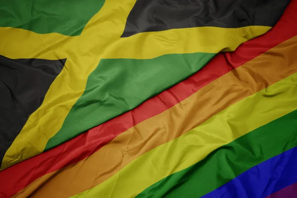 挥舞着五颜六色的同性恋彩虹旗和牙买加国旗. — 图库照片