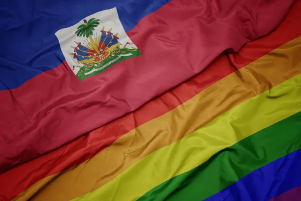 Zwaaiende kleurrijke Gay regenboog vlag en nationale vlag van Haïti. — Stockfoto