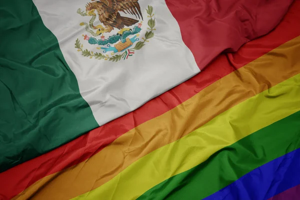 Ondeando colorida bandera arco iris gay y bandera nacional de México . — Foto de Stock