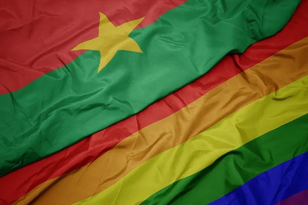 Waving colorful gay rainbow flag and national flag of burkina faso. — Stock Photo, Image