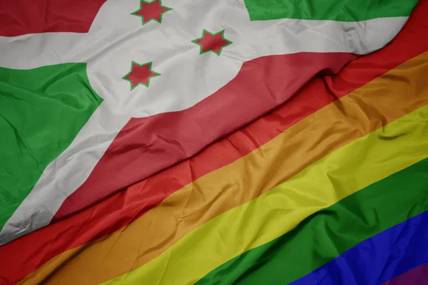 Waving colorful gay rainbow flag and national flag of burundi . — Stock Photo, Image