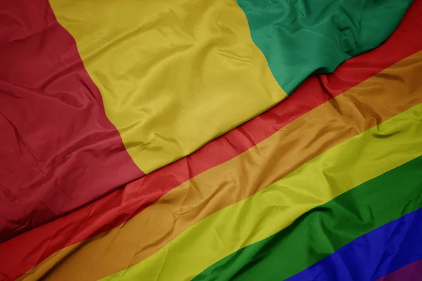 Ondeando colorida bandera arco iris gay y bandera nacional de Guinea . — Foto de Stock