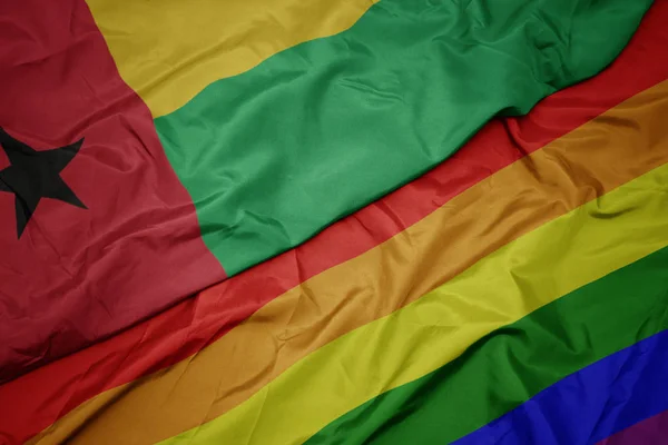 挥舞着五颜六色的同性恋彩虹旗和几内亚比绍国旗. — 图库照片