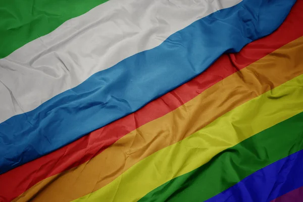 waving colorful gay rainbow flag and national flag of sierra leone.