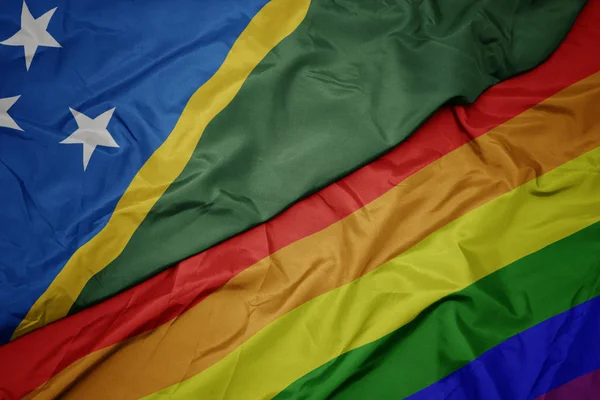 Integetett színes meleg szivárványos zászló és a nemzeti zászló a Salamon-szigetek. — Stock Fotó