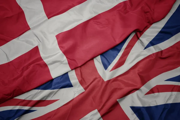 Viftende, fargerikt flagg for store briter og nasjonalt denmark . – stockfoto