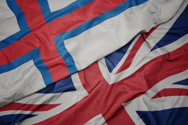 Falujące kolorowe flagi Wielkiej Brytanii i flagi narodowej Wysp Owczych. — Zdjęcie stockowe