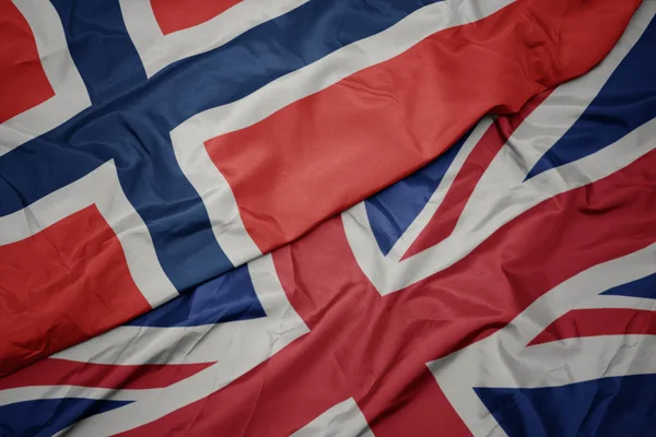 Zwaaiende kleurrijke vlag van Groot-Brittannië en de nationale vlag van Noorwegen. — Stockfoto
