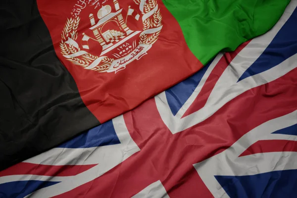 Ondeando colorida bandera de Gran Bretaña y bandera nacional de Afganistán . — Foto de Stock
