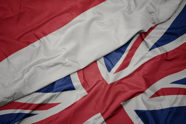 Acenando bandeira colorida de grande britânico e bandeira nacional da indonésia . — Fotografia de Stock