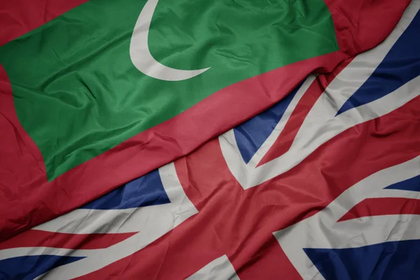 Махаючи барвистим прапором Великої Британії та національного прапора мальдів . — стокове фото