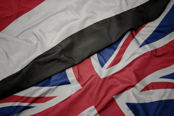Acenando bandeira colorida de grande Grã-Bretanha e bandeira nacional do Iêmen . — Fotografia de Stock