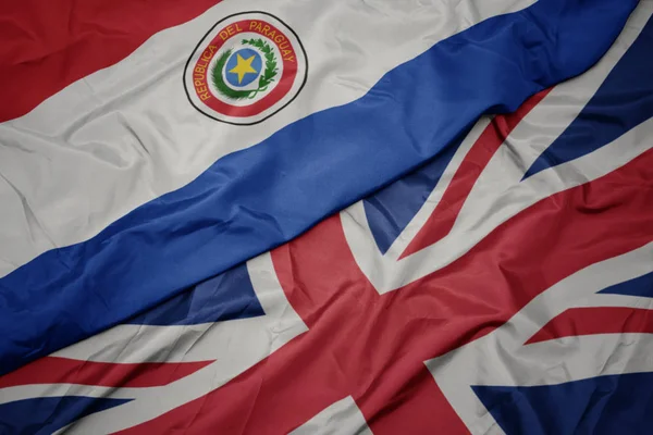 Falujące kolorowe flagi Wielkiej Brytanii i flagi narodowej Paragwaju. — Zdjęcie stockowe