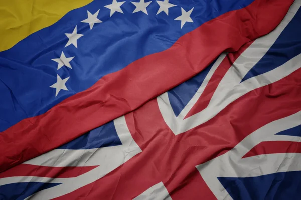 Schwenken bunte Fahne von Großbritannien und Nationalflagge von Venezuela. — Stockfoto