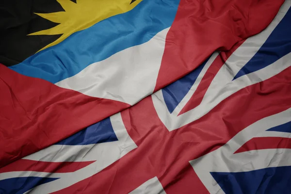Размахивая красочным флагом Великобритании и национальным флагом Антигуа и Барбуды . — стоковое фото