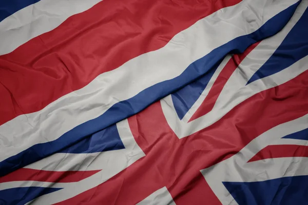 Ondeando colorida bandera de Gran Bretaña y bandera nacional de Costa Rica . —  Fotos de Stock