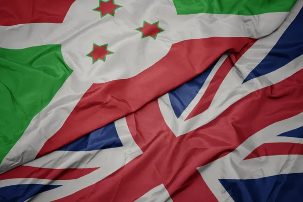 Acenando bandeira colorida de grande britânico e bandeira nacional do burundi . — Fotografia de Stock
