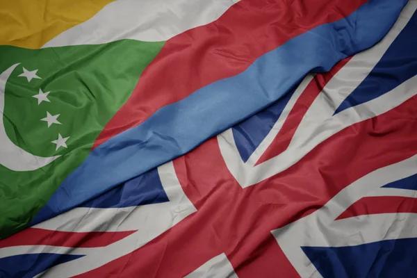 Waving colorful flag of great britain and national flag of comoros. — Stock Photo, Image