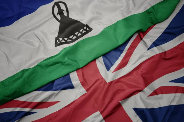 Acenando bandeira colorida de grande britânico e bandeira nacional de lesotho . — Fotografia de Stock