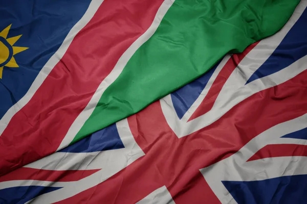 Acenando bandeira colorida de grande britânico e bandeira nacional da Namíbia . — Fotografia de Stock