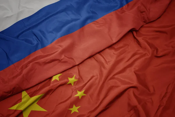 Размахивая красочным флагом Китая и национальным флагом России . — стоковое фото
