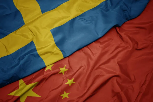 Falujące kolorowe flagi Chin i flagi narodowej Szwecji. — Zdjęcie stockowe