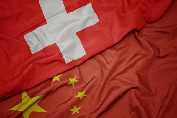 Ondeando colorida bandera de China y bandera nacional de Suiza . — Foto de Stock