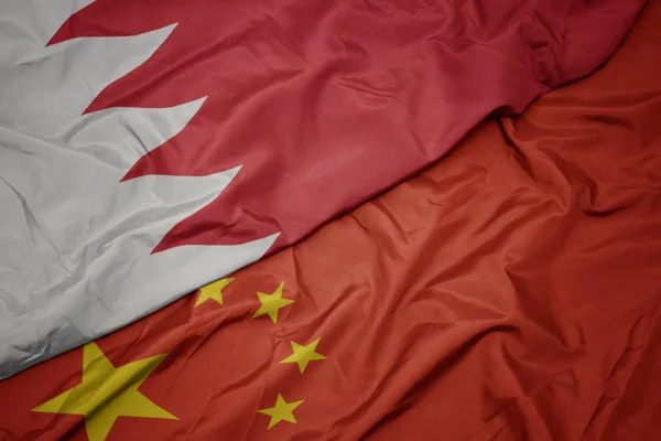 waving colorful flag of china and national flag of bahrain.