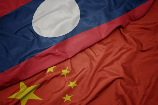 Хвилястий барвистий прапор Китаю і національний прапор лаосу . — стокове фото