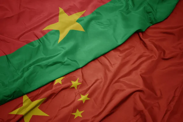 Ondeando colorida bandera de China y bandera nacional de Burkina faso . — Foto de Stock