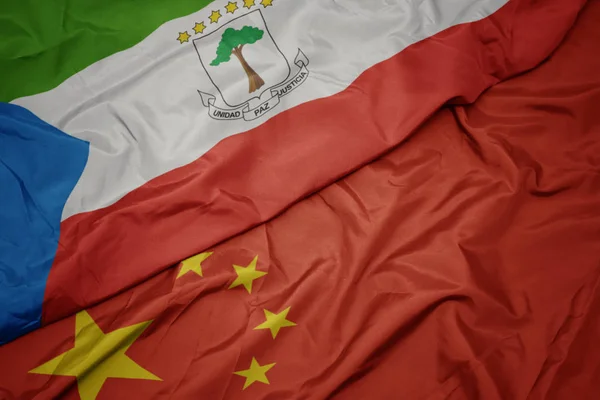 Mávající barvitá vlajka Číny a národní vlajka rovníkových guinejí. — Stock fotografie