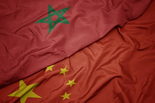 waving colorful flag of china and national flag of morocco.
